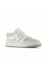 Sneakers with a light gray and cream suede upper, white accents, flat laces, padded collar, and a textured rubber sole.