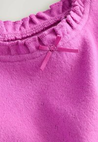 Maglione lavorato a maglia rosa con un colletto arricciato e un piccolo dettaglio in satin a forma di fiocco. Texture morbida con un aspetto fine e leggermente peloso.