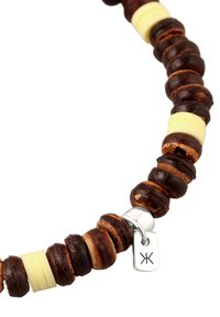 Bracelet en perles de bois brun avec des accents jaunes alternés et une étiquette en argent portant un symbole. Texture lisse avec un design arrondi.