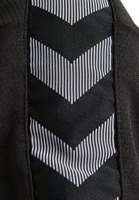 Sort stof med et struktureret, chevron-mønster i hvid. Glatte og ribbede teksturer skifter i designet, hvilket fremhæver kontrasten.