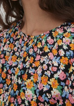 Schwarzer Stoff mit Blumenmuster in einer Mischung aus orangefarbenen, rosa und blauen Blumen; hat ein plissiertes Design und einen runden Ausschnitt.