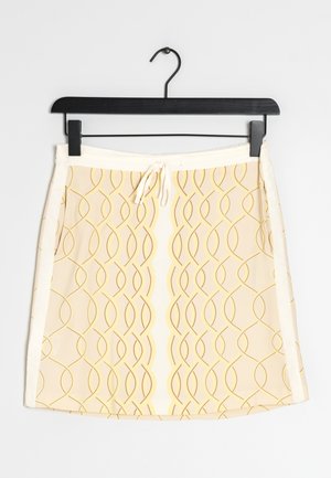 Jupe jaune clair avec un motif ondulé en jaune plus foncé. Elle présente une taille avec cordon de serrage et une texture lisse. Accrochée à un cintre noir.