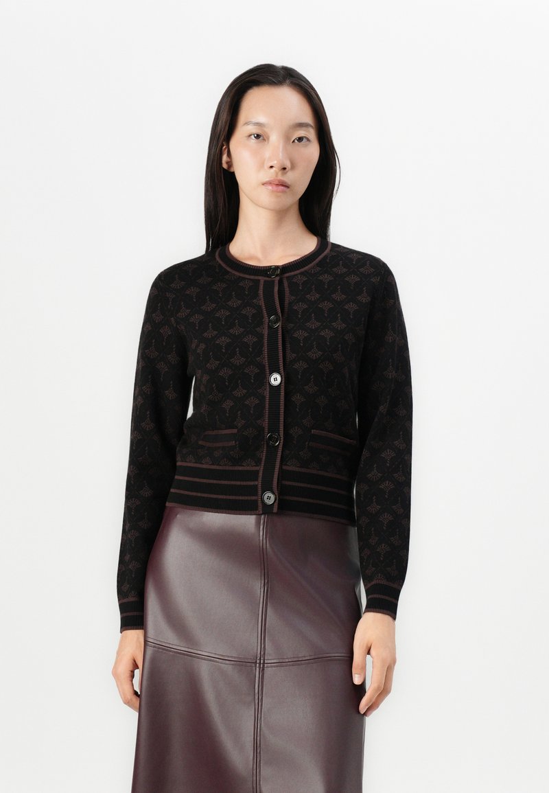 Gilet en tricot noir avec un motif répétitif, col rond et bord contrastant bordeaux ; doté de boutons noirs et de poignets côtelés.