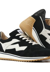 Schwarze und weiße Wildledersneaker mit Gummisohle, weißen Zickzack-Seitendetails, weißen Schnürsenkeln und gepolstertem Kragen mit glitzerndem schwarzen Absatz.