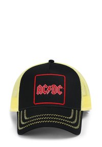 Melnā cepure ar dzeltenām sieta malām, kurā ir sarkans izšūts AC/DC logo taisnstūra ietvarā un kontrastējoša dzeltena šūšana.