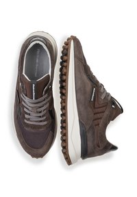 Sneaker in suede marrone con accenti in rete scura, sovrapposizioni testurizzate e suole in gomma chiara con punte arrotondate per una migliore aderenza. Lacci grigi.
