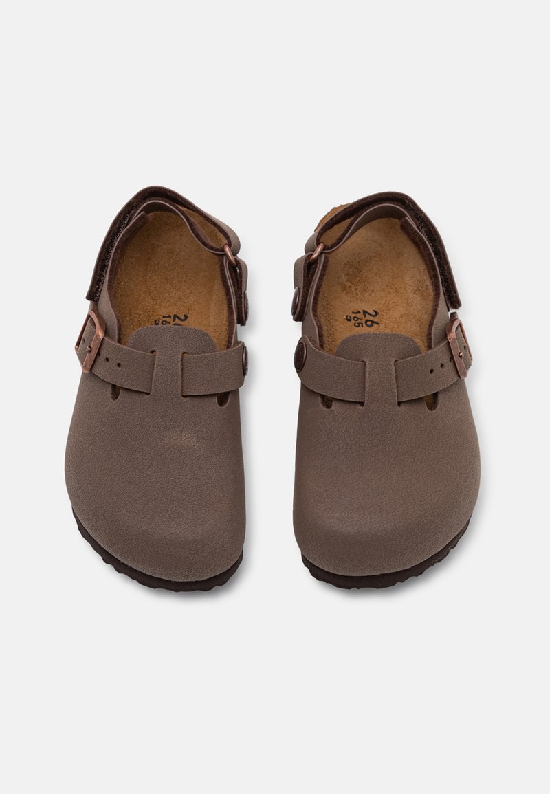 Brązowe skórzane klumpki z regulowanym zapięciem, profilowaną wkładką oraz teksturowaną podeszwą. Mają okrągły czubek i gładkie wykończenie.