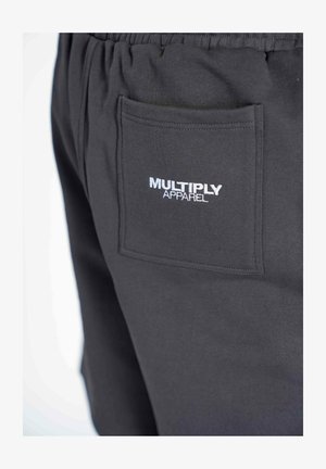 Mustat verkkarit, joissa on joustava vyötärö, takatasku ja valkoinen "MULTIPLY APPAREL" brodeerattu logo. Pehmeä rakenne.