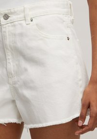 Witte denimshorts met een rafelige zoom, voorzien van een klassieke vijf-pocketontwerp en metalen knoopsluiting. Gladde textuur en aansluitende pasvorm.