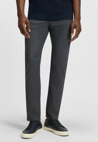 Grå byxor med slim fit, tillverkade av ett slätt tyg. Kompletterade med svarta sneakers med en krämfärgad gummisula.