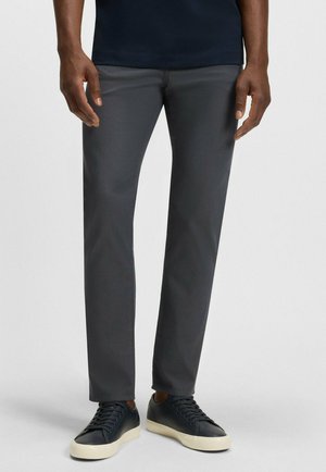 Grå byxor med slim fit, tillverkade av ett slätt tyg. Kompletterade med svarta sneakers med en krämfärgad gummisula.