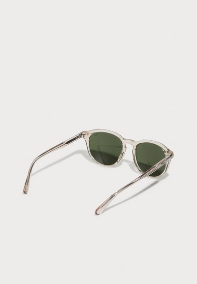 Ochelari de soare cu rame transparente și lentile verzi. Au o formă de ochi de pisică, cu brațe argintii elegante și fără branding vizibil.