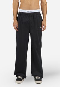 Black wide-leg pants with an elastic waistband featuring a white PEGA DOR logo, made of soft fabric, suitable for casual wear.
