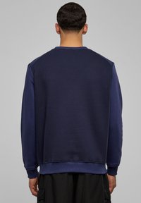 Tumesinine pusa soonikkoega ümara kaelusega, pikkade varrukatega ja siledast materjalist. Erinevat värvi varrukad ja sirge alläär.