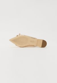 Ballerines dorées à bout pointu avec un dessus texturé et un petit nœud décoratif. La semelle lisse combine des tons beiges et dorés, indiquant un design léger.