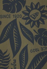 Stoffdruck mit dunkelblauen Blumen- und Blattmustern auf einem olivgrünen Hintergrund, in den das Text „SINCE 1920“ integriert ist.