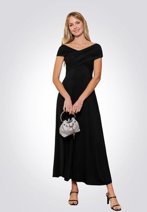 Abito lungo nero, scollato sulle spalle, con dettagli drappeggiati. Borsa argentata texturizzata con manico circolare e sottili embellishments.