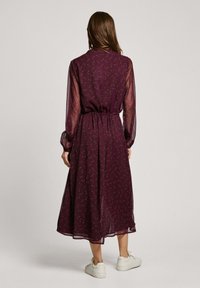 Mauve midi šaty s kvetinovým vzorom, priesvitné dlhé rukávy, elastický pás a prúdiaca látka, doplnené zberaným lemom. V kombinácii s bielymi teniskami.