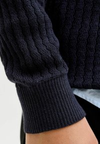 Námořnický pletený svetr s texturovaným, žebrovaným designem. Manžeta má kontrastní žebrovaný prvek. Vyrobeno z měkké, elastické látky.