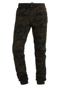 Camo tepláky v tmavě zelené a černé barvě, s elastickým pasem na šňůrku, zúženým střihem nohavic a žebrovanými manžetami.