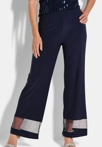 Marineblauwe wijde broek van zacht materiaal, met doorzichtige mesh accenten aan de zoom en een elastische tailleband voor comfort.