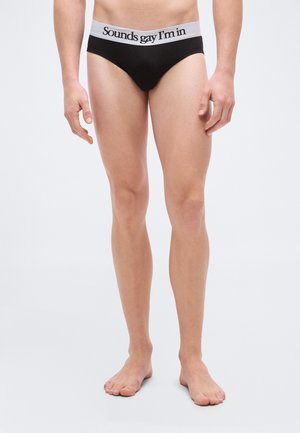 Sorte bomuldstrusser med en grå elastik med teksten "Sounds gay I'm in." Enkelt design, tætsiddende pasform, minimalistisk stil og blød tekstur.
