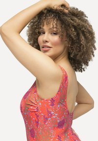  kirkas punainen uimapuku, jossa on sinisiä ja purppuranvärisiä kukkakuvioita. Ominaisuuksiin kuuluu matala selkä, leveät hihnat ja sileä, kiiltävä tekstuuri.