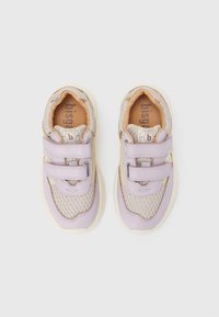 Παιδικά αθλητικά παπούτσια σε μπεζ και ανοιχτό μωβ με ύφασμα δίχτυ και διπλές λουρίδες βέλκρο, δείχνονται από πάνω σε λευκό φόντο.