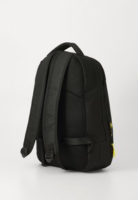 Black backpack with padded mesh back, dual shoulder straps, and a zippered pocket featuring yellow pull tab. Compact and structured design.
