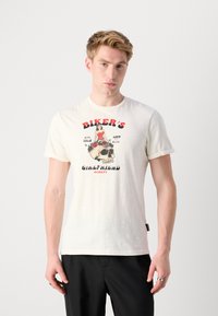 Camiseta de algodón blanco con mangas cortas, que presenta una impresión gráfica de una mujer sobre una calavera, con el texto "NOVIA DEL MOTORISTA" en acentos rojos y negros.