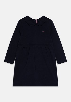 Donkerblauwe babyjurk met lange mouwen, Peterseliekraag, geplooide rok en klein geborduurd logo op de borst.