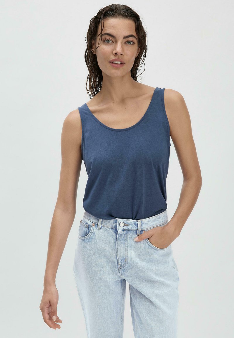 Navyblauw tanktop van zacht materiaal met een ronde halslijn en brede bandjes, gecombineerd met lichtblauwe high-waisted jeans.