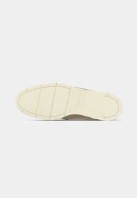 Brown suede shoe sole with a textured white rubber bottom featuring horizontal grooves and rounded toe shape.