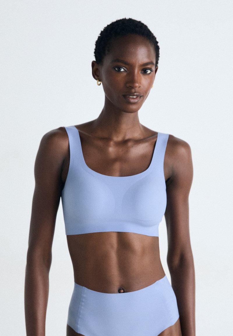 Reggiseno sportivo azzurro chiaro con spalline larghe e design senza cuciture. Tessuto morbido ed elastico con finitura opaca. Nessuna meccanica o decorazione visibile.