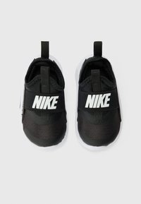 Mustat Nike-kengät, joissa on joustava hihna, teksturoitu päällinen mesh- ja synteettisistä materiaaleista, valkoinen pohja ja vetonauhat helpottamaan pukemista.