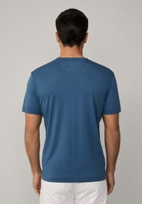 Modrá krátká trička s krátkým rukávem a kulatým výstřihem, vyrobená z měkké látky. Má jednoduchý design a hladkou strukturu bez viditelných vzorů.