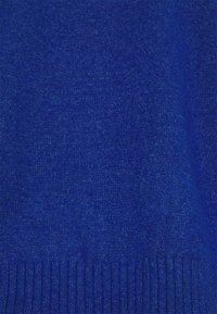 Blå stickad tröjfabric med en slät textur och ribbad nederkant, med en rik färgdjup och en enhetlig vävning.