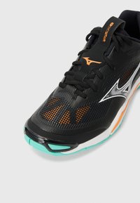 Black athletic shoe with mesh upper, orange accents, and turquoise sole. Features prominent branding and textured detailing for grip.