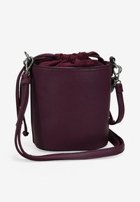 Bolso de cubo redondo en cuero burdeos oscuro con un acabado texturizado. Cierre de cordones y correa para el hombro ajustable. Accesorios en tono plateado.