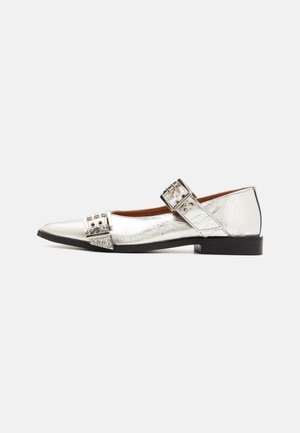 Zapato plano metálico plateado con punta afilada, superficie texturizada, correa de doble hebilla y un pequeño tacón negro. Destaca por su acabado brillante.