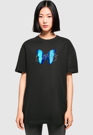 Svart bomull oversized t-skjorte med en blå sommerfugl grafikk og ordet "Sommerfugl" i hvit kursiv skrift over brystet.