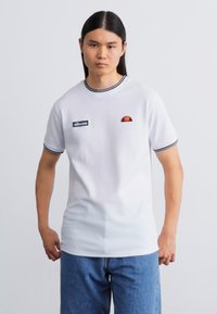 Hvid kortærmet t-shirt med sort kant, som har et lille rødt og orange logo på brystet og et sort mærke på siden.