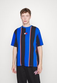 Tricou scurt cu mânecă, bleu și negru cu dungi, având accente neon și un mic patch cu logo pe piept. Croială lejeră, din material de bumbac.