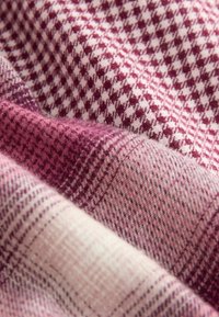 Vävt tyg med ett rutigt mönster i nyanser av djup rosa och ljus rosa, med en mjuk, texturerad yta.
