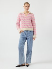 Maglione a zigzag rosa e crema con scollo a V e maniche lunghe, abbinato a jeans a gamba larga blu chiaro e scarpe nere con punta a stiletto.