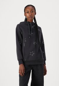Sudadera de color gris oscuro con estampado de estrellas, con cordón en el cuello, puños acanalados y bolsillo. Confeccionada en tela suave y de corte relajado.