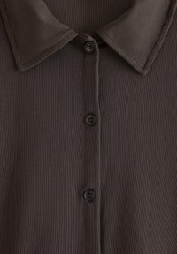 Polo di colore grigio scuro con tessuto lavorato, dotata di colletto e cinque bottoni coordinati sul davanti.