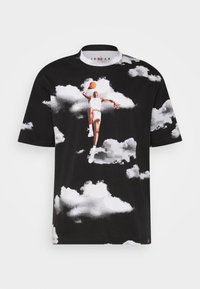 T-shirt en coton noir avec un motif représentant un joueur sautant avec un ballon de basket parmi des nuages blancs. Col rond et manches courtes.