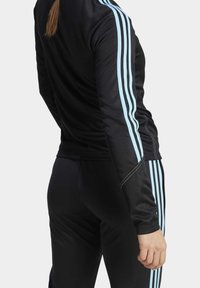 Schwarzer sportlicher Trainingsanzug mit hellblauen Streifen an den Ärmeln und Hosen, aus glattem Material gefertigt, mit taillierter Passform und dezenten Nähten.
