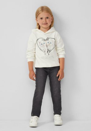 Felpa bianca con un design a forma di cuore che presenta due gattini e il testo "AMICI." Abbinata a jeans scuri e sneakers bianche.